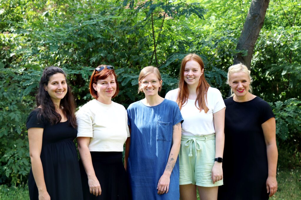 Das Team der Netzwerkstelle "Lernen durch Engagement" Sachsen-Anhalt steht vor einem grünen Hintergrund